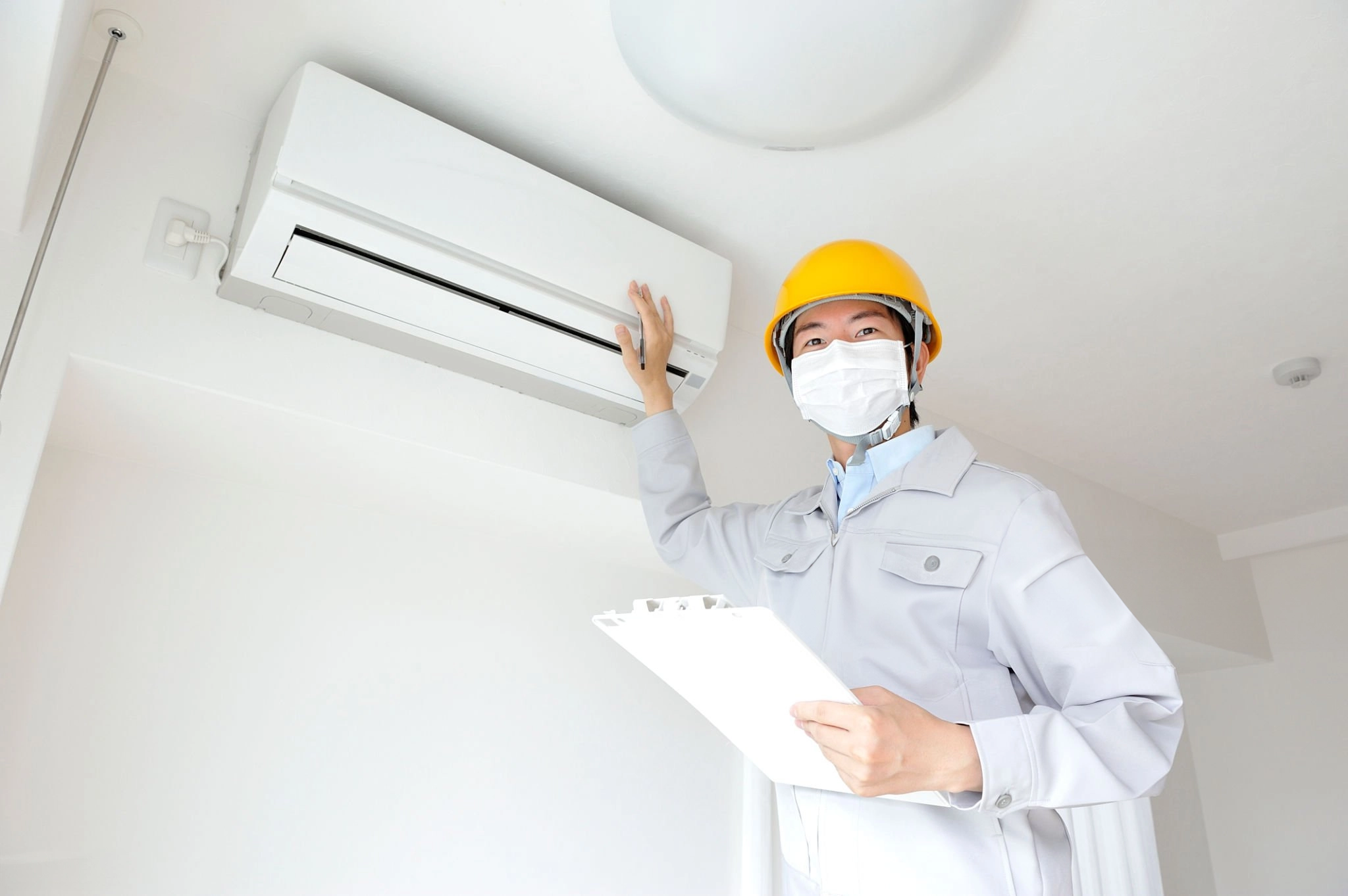 Man in white shirt holding air conditioner unit