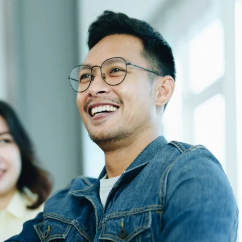 Man with glasses shaking hands and smiling